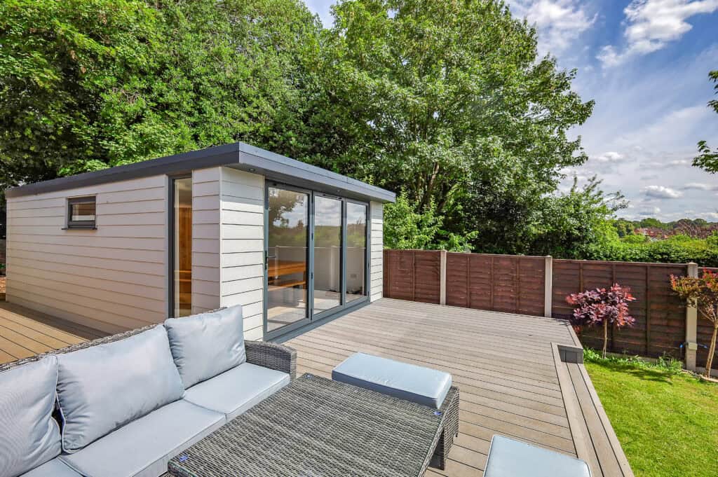 Modern garden room with glass doors on a raised decking terrace in a landscaped garden