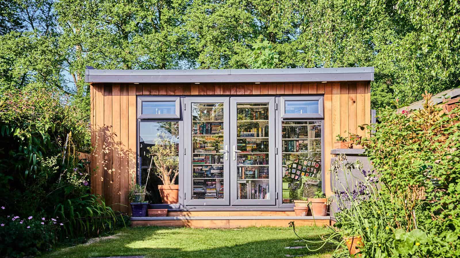 Timber garden pod with storage, glazed double doors and windows, surrounded by garden planting