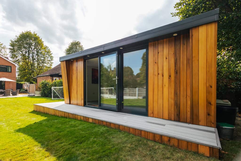 Modern timber garden room with full-height glazed doors and a raised decking platform