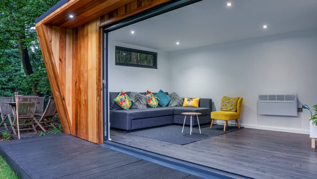 Garden room living area with a sofa, armchairs and coffee table, viewed through its open entrance